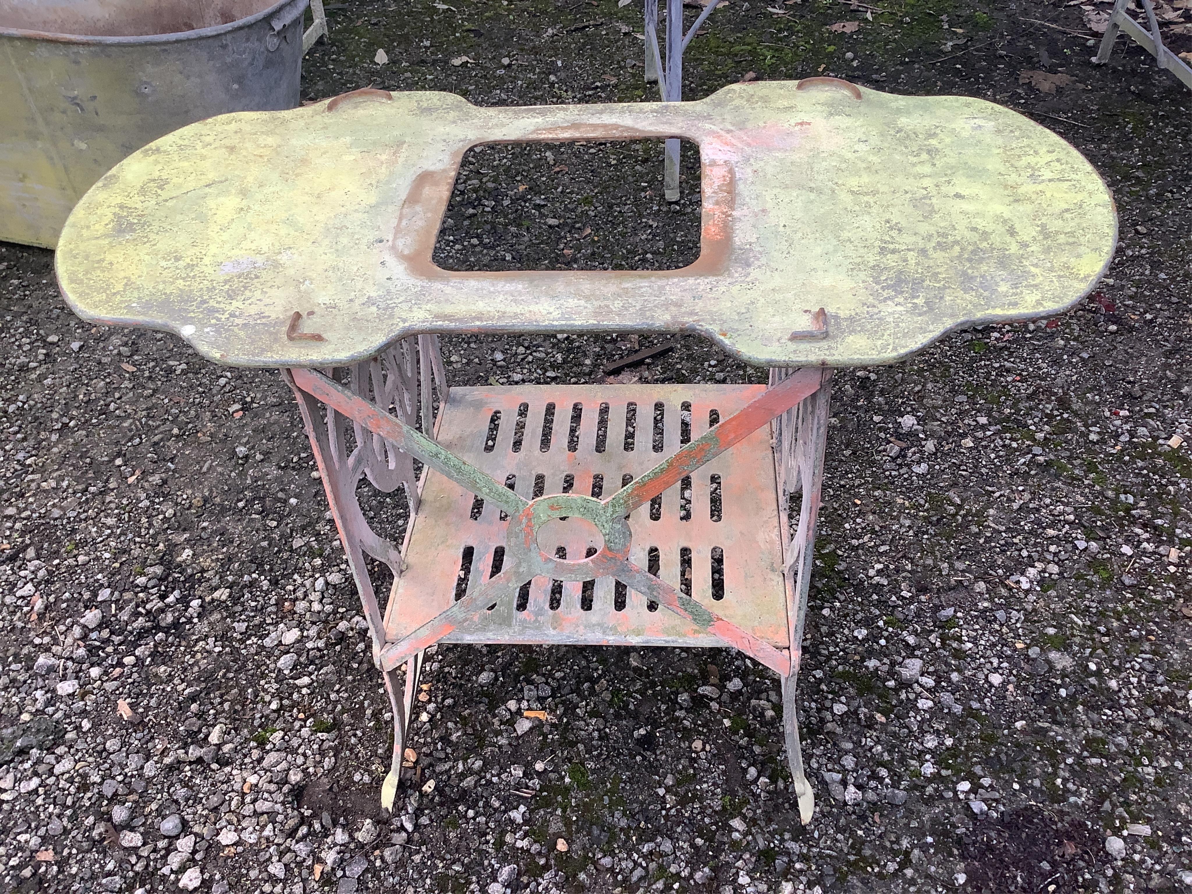 A small white painted cast metal two tier table, with a shaped top, width 78cm, height 59cm. Condition - fair